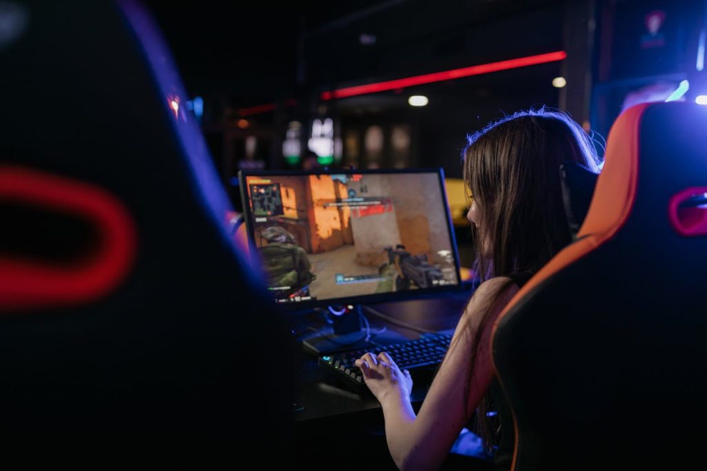 A woman is deeply engaged in playing computer games indoors, highlighting the gaming lifestyle.